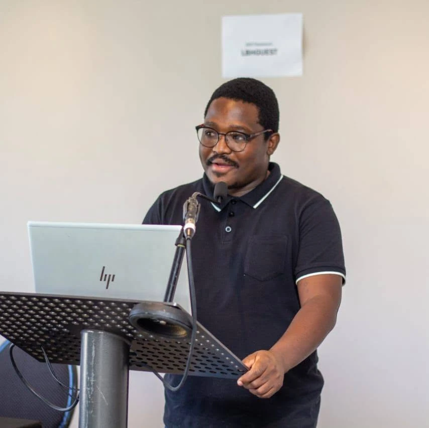 Thabiso Naleli speaking at a lectern with a laptop