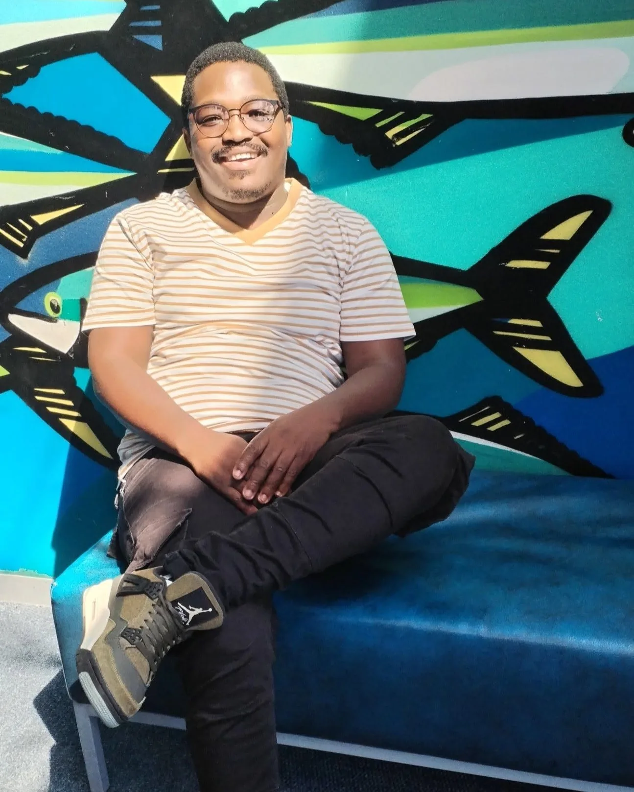 Thabiso Naleli seated in front of a colourful mural