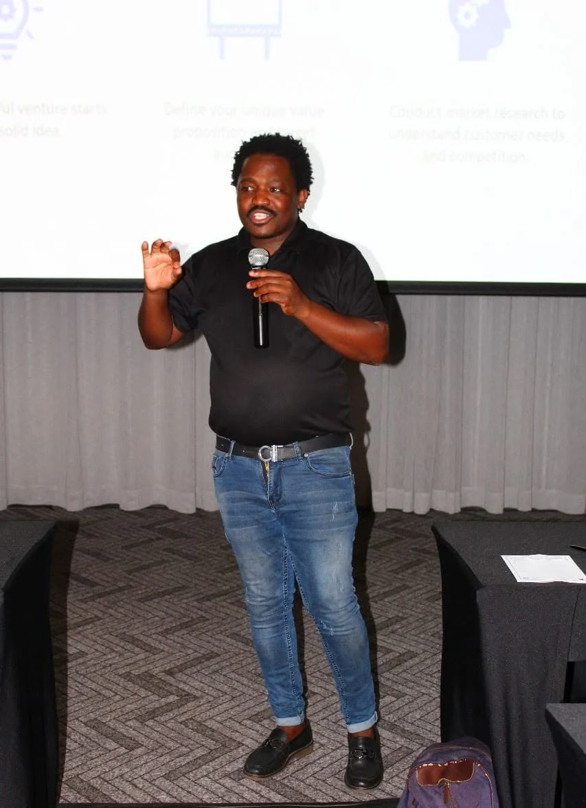 Thabiso Naleli speaking with a microphone in front of a presentation screen